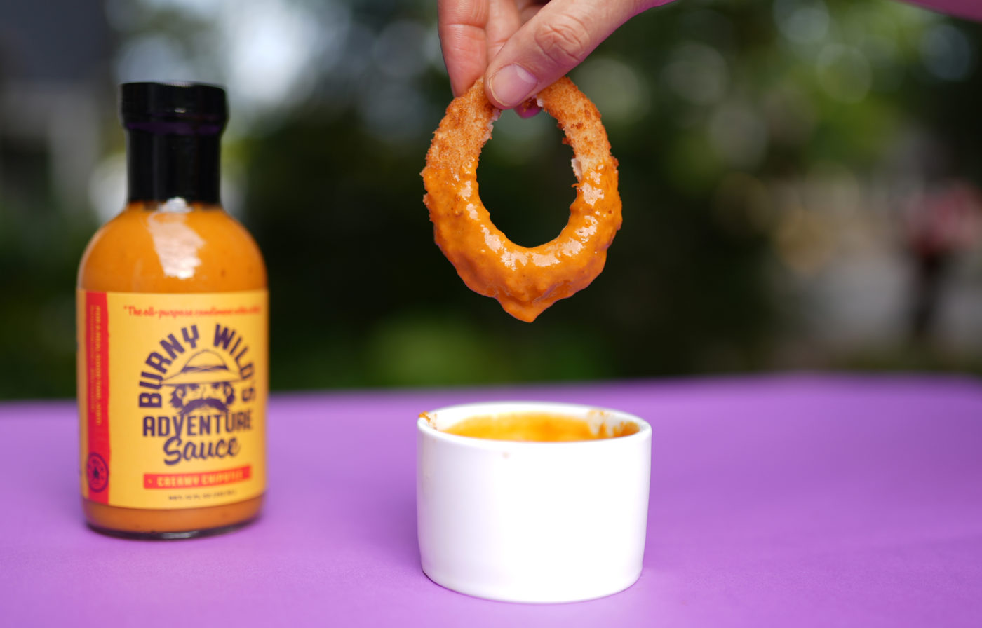 Crispy Onion Ring Dipped in Burny Wild's Adventure Sauce. More versatile than any hot sauce. Bottled in Raleigh, NC.