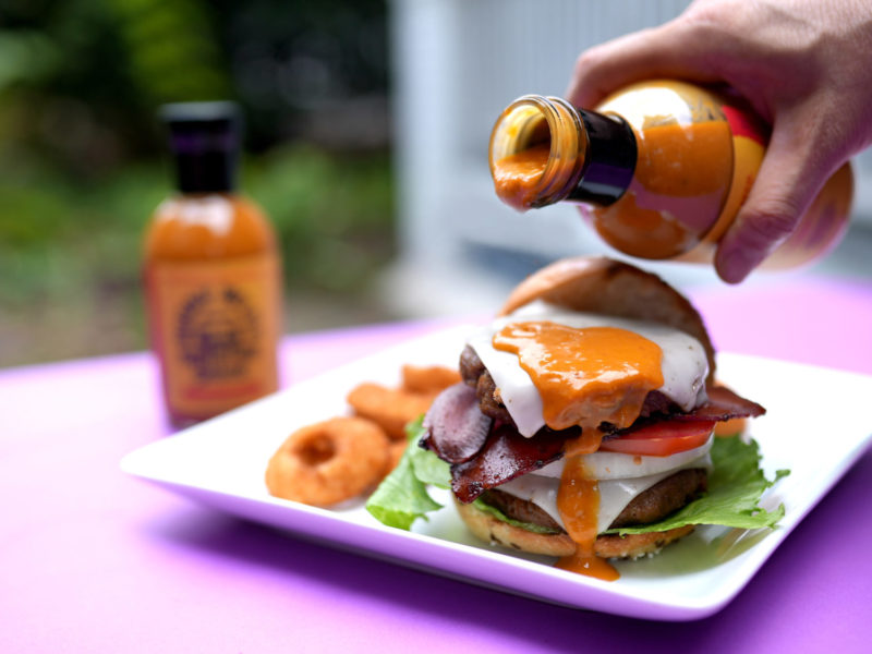 Burny Wild's Adventure Sauce being poured over a vegan bacon burger